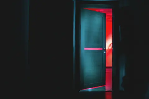 A door ajar with red light behind it