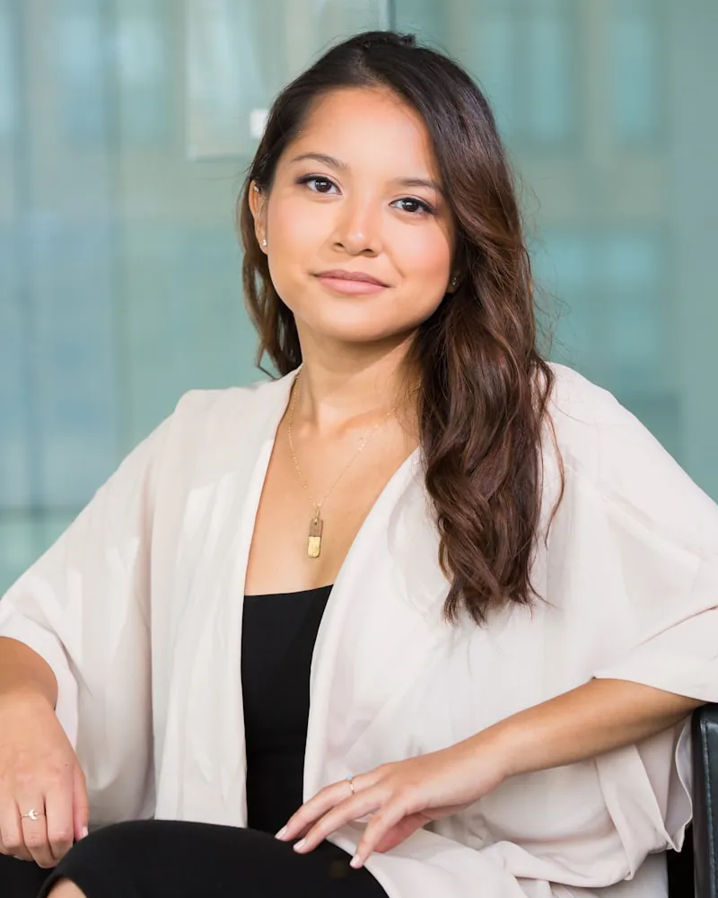 A woman with long dark hair in a cream cardigan