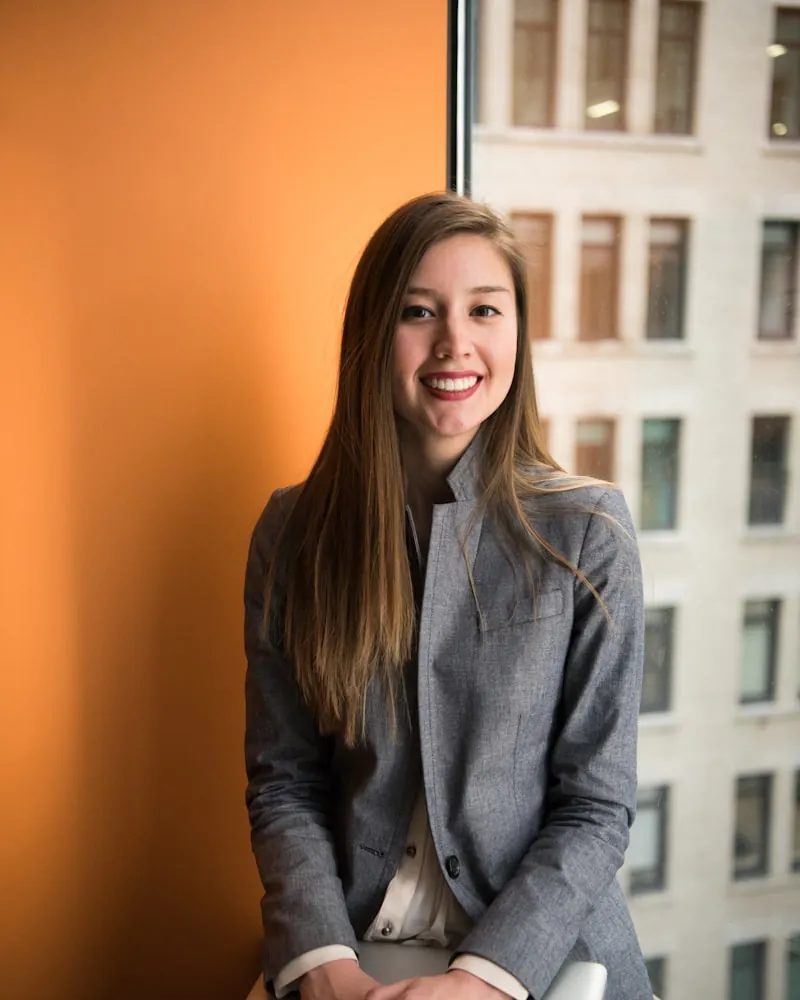 A smiling woman with long straight hair in a grey blazer