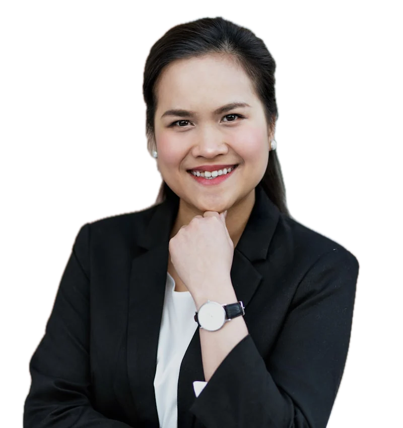 A smiling woman in a black blazer with her hand at her chin