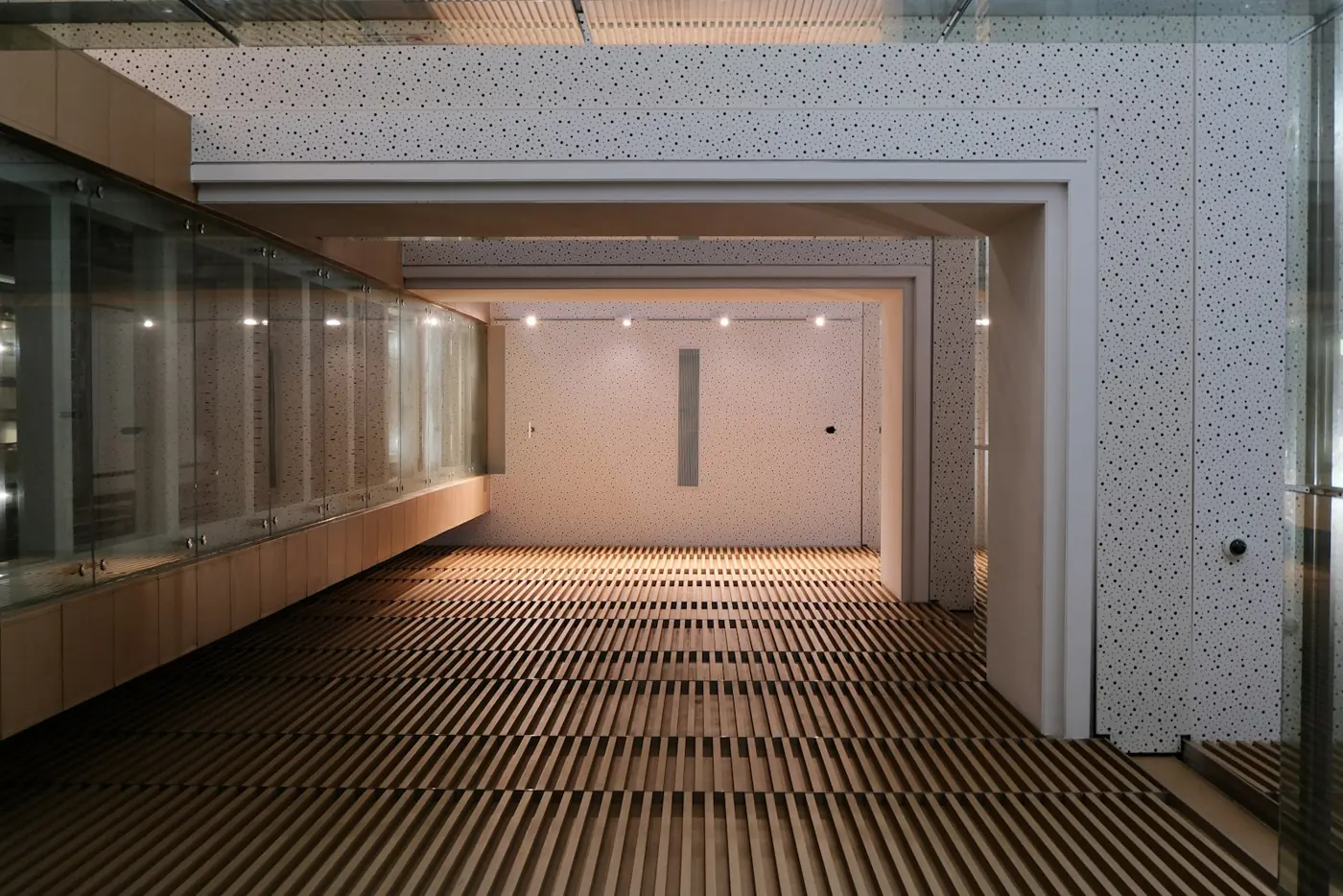 A long corridor with a slatted wooden floor and glass cases