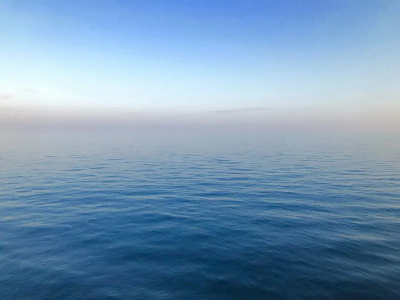 بحر أزرق هادئ يلتقي بأفق شاحب