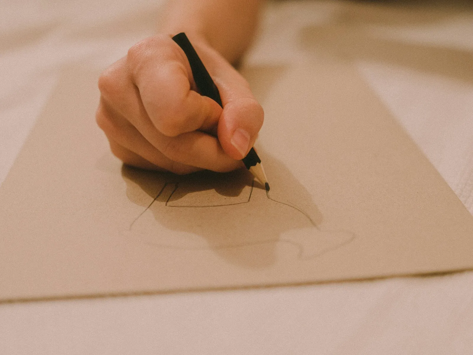 يد ترسم بقلم رصاص على ورق بني