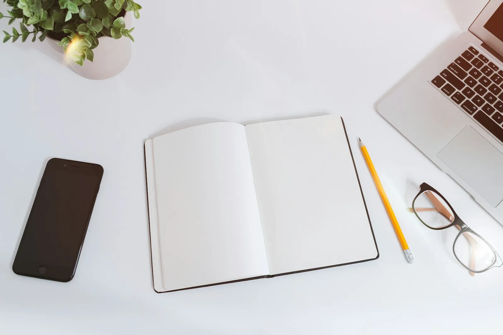 دفتر مفتوح وقلم رصاص ونظارة على مكتب أبيض