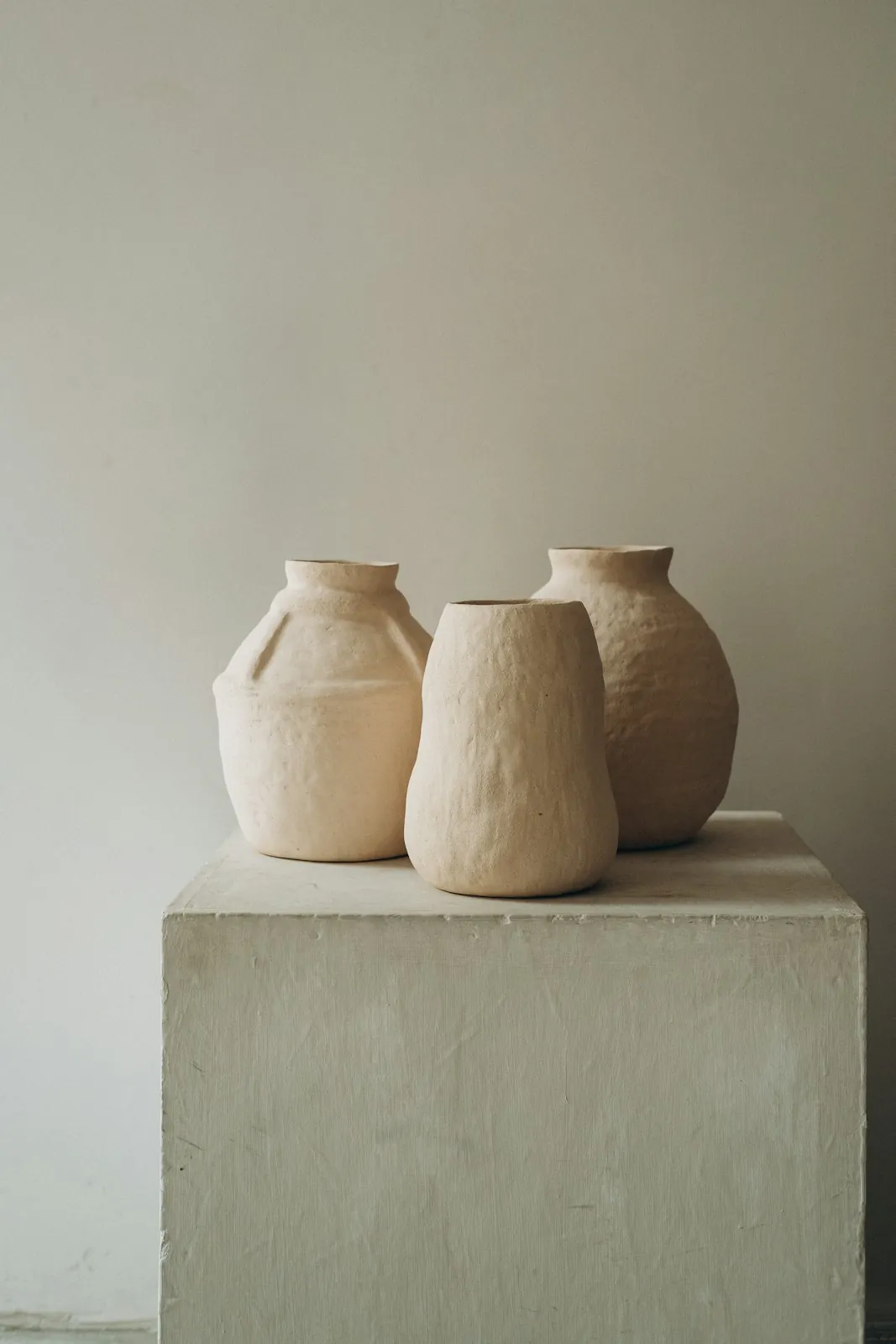 ثلاث مزهريات من الطين على قاعدة خرسانية