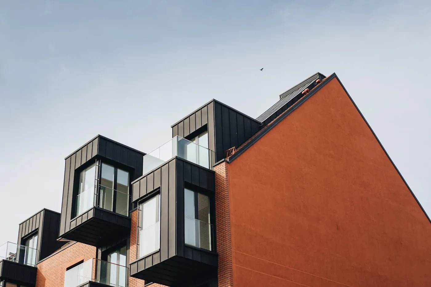 Modular housing with dark cladding beside a brick gable